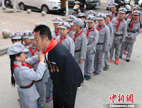 受谷殿明血雷鋒事跡的感染，雷鋒小標兵為這位“活雷鋒”爺爺系上紅領巾。　郭園 攝