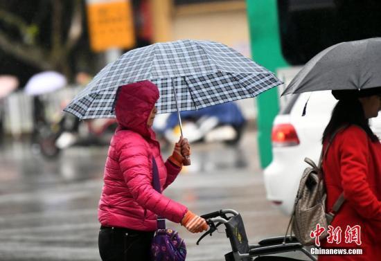 資料圖：昆明市區里身著羽絨服冒雨趕路的民眾。 中新社記者 李進紅 攝