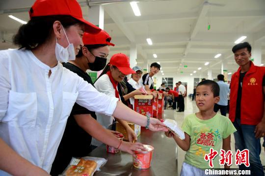 8月24日，志愿者在濰坊壽光市營(yíng)里鎮(zhèn)第二初級(jí)中學(xué)安置點(diǎn)為災(zāi)民發(fā)放救援物資。　梁犇 攝