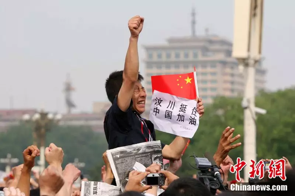 2008年5月19日，北京天安門廣場上的民眾為地震遇難者默哀，一位來自四川的男子高舉右手為家鄉(xiāng)加油。中新社記者 富田 攝